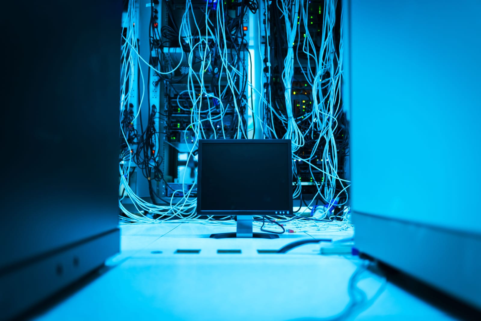 Tangled network cables plugged into a server rack in a data room